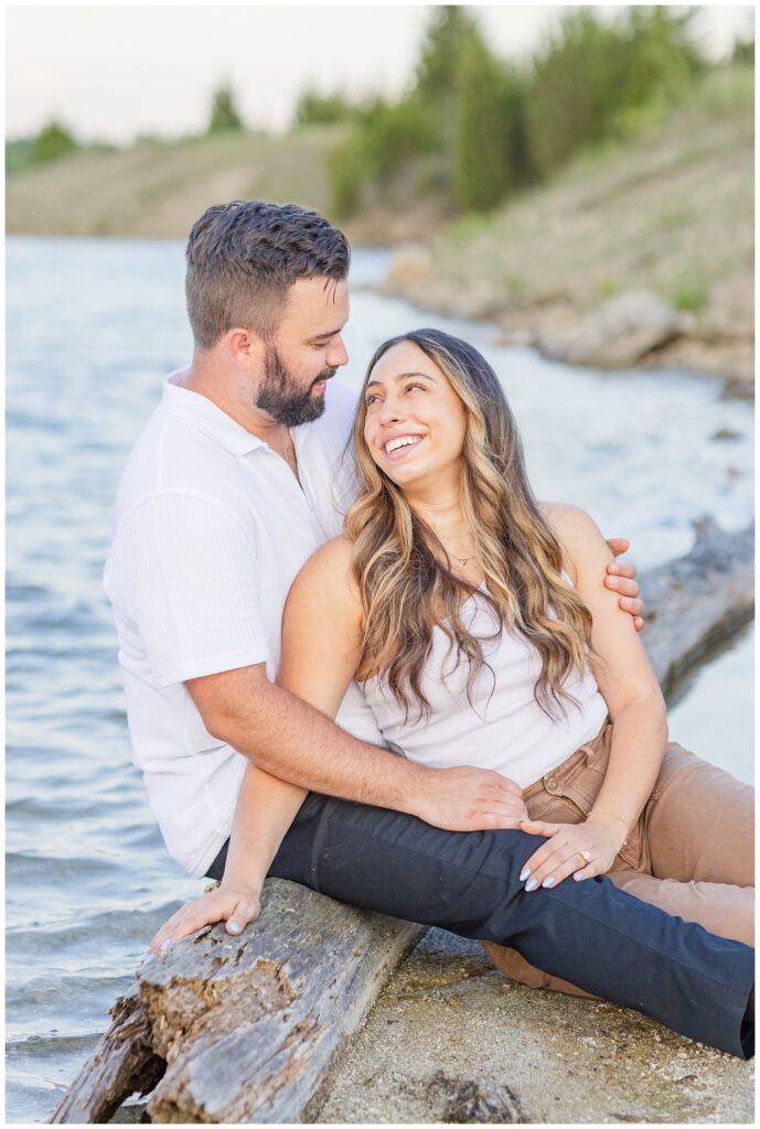 engaged couple sitting on a log in the lake at Silver Rock Quarry