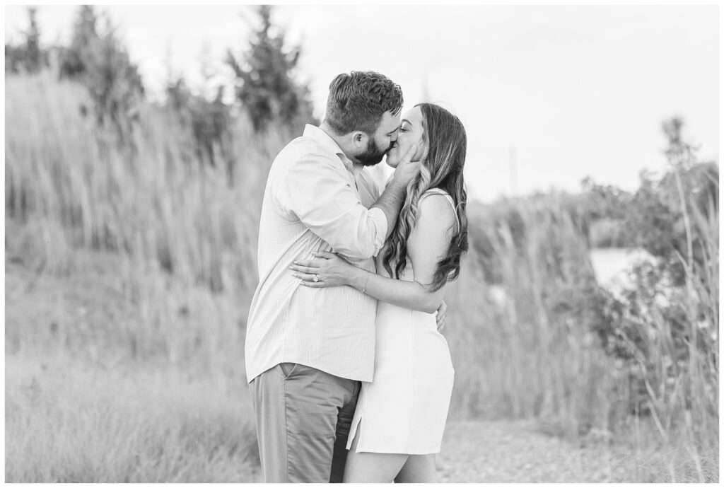 couple kissing among the grass next to the lake at Silver Rock Quarry