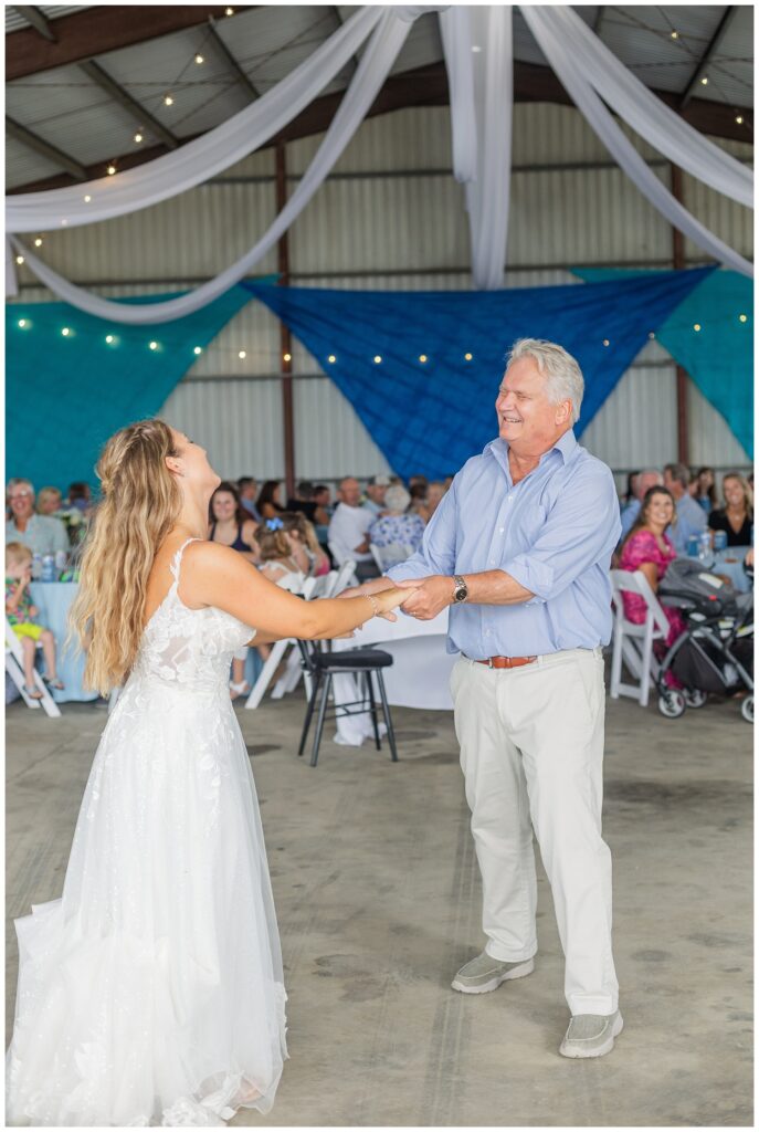 bride's dad twirling the bride around the dance floor in a barn on family farm