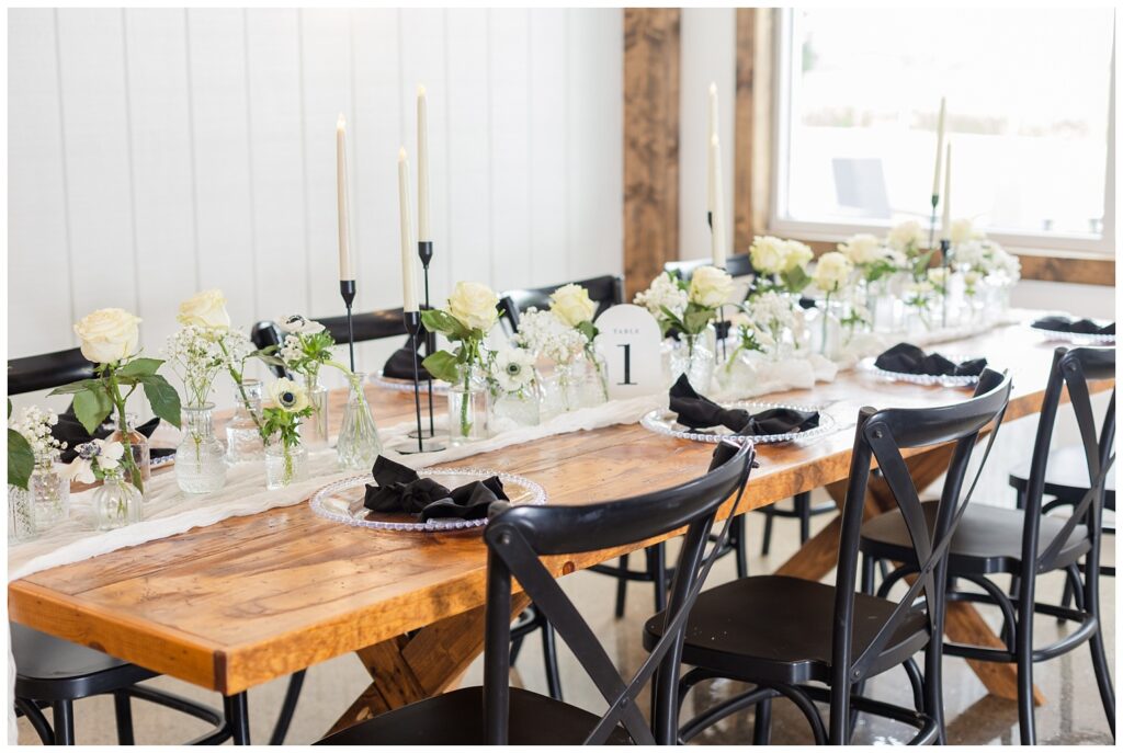 wooden table with black chairs decorated with glass vases and white roses