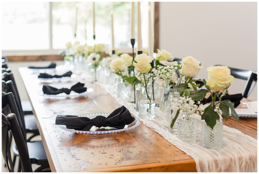 reception table with glass vases and white roses at Barn at Seneca Hills