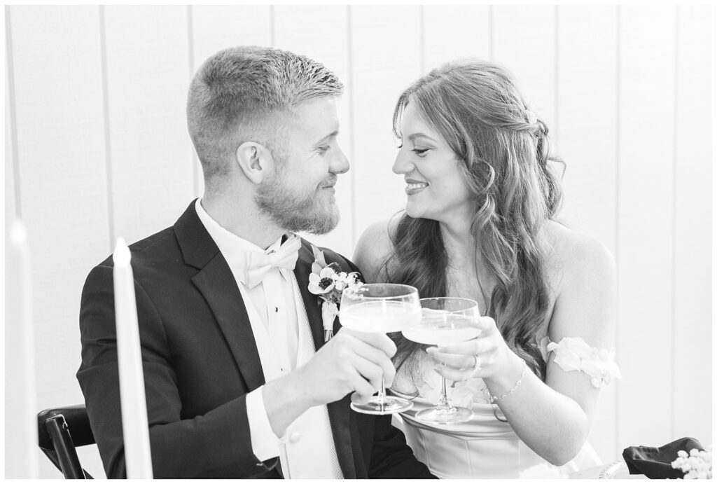 wedding couple toasting champagne glasses at the reception table at venue