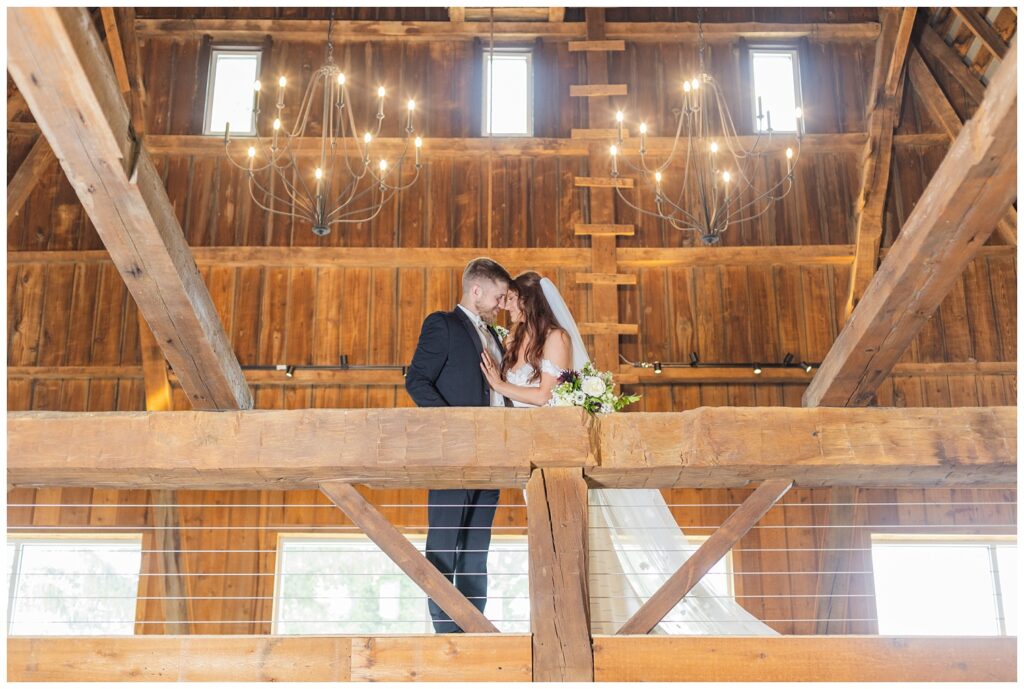 bride and groom posing on the balcony  under chandelier lights at barn venue