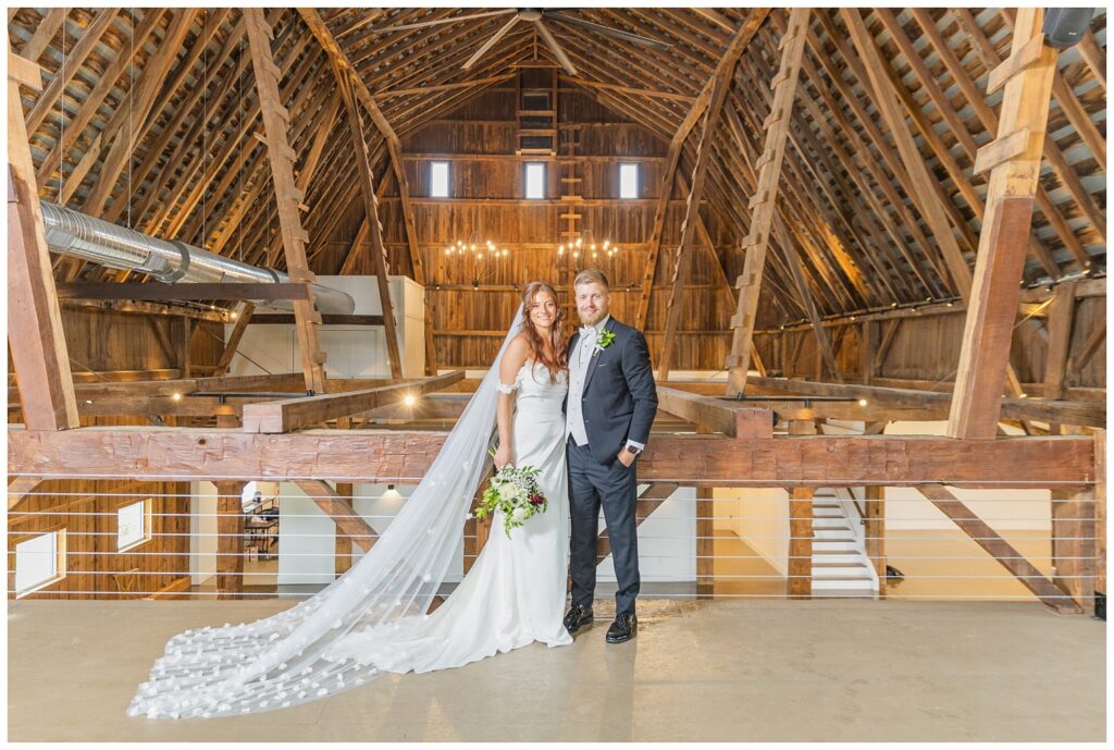 bride and groom posing on the balcony  under chandelier lights at barn venue