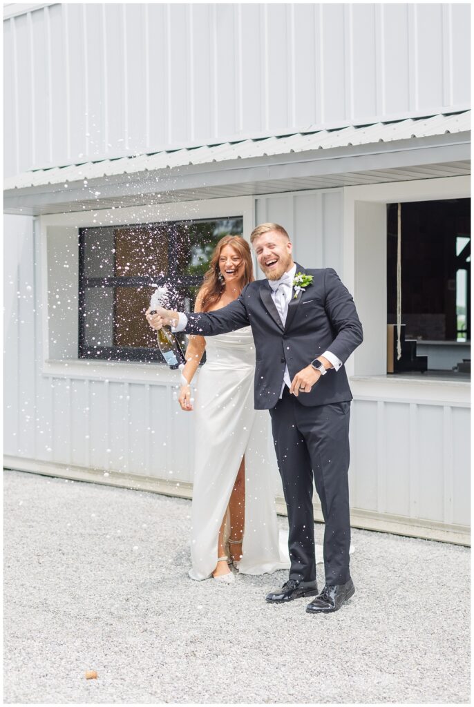 bride and groom spraying a champagne bottle at the outside bar on the patio