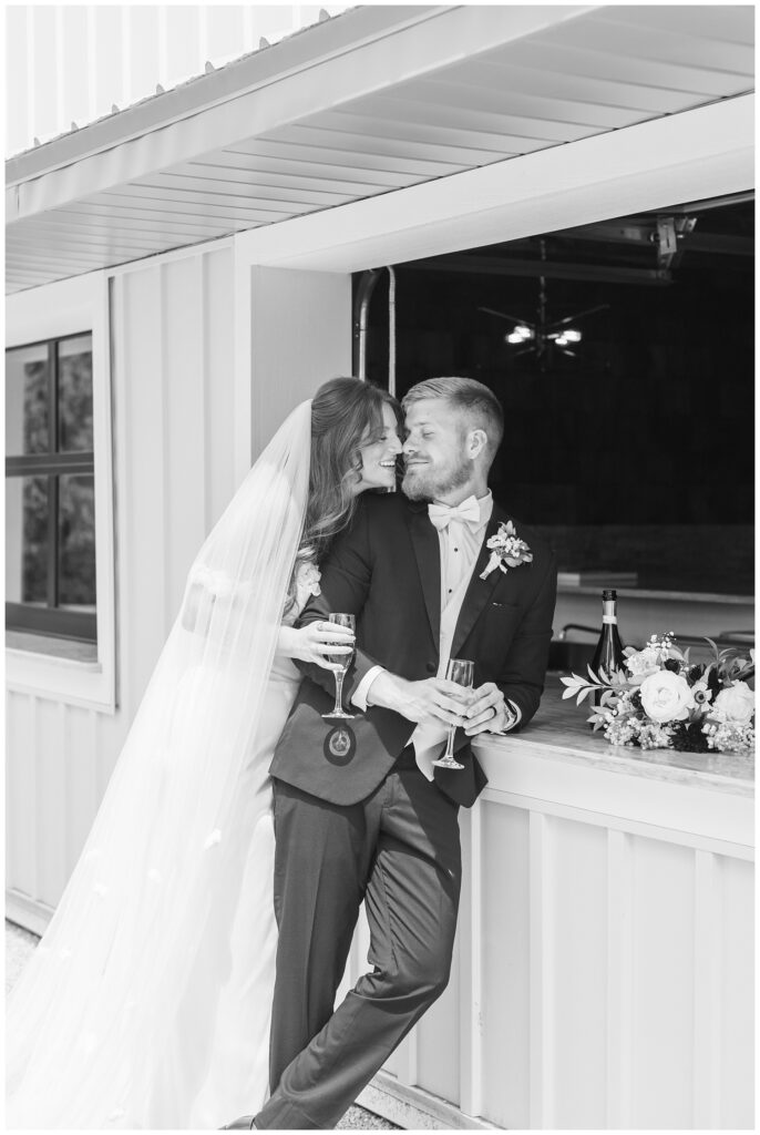 bride and groom leaning against the bar while holding champagne 