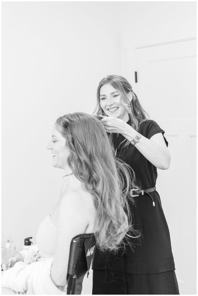 bride laughing while getting her hair done in the bridal suite at The Barn at Seneca Hills