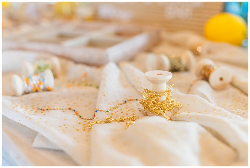 gold chain wrapped around a wooden spool on a gold and white tablecloth