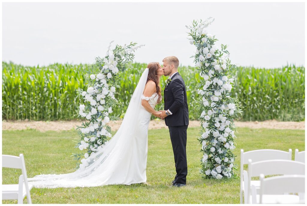 wedding couple share kiss in front of the ceremony floral arch in Tiffin, Ohio