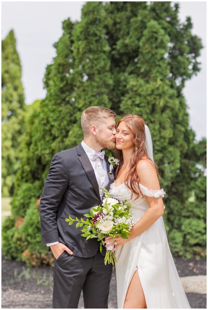 groom kissing the bride on the cheek outside at The Barn at Seneca Hills