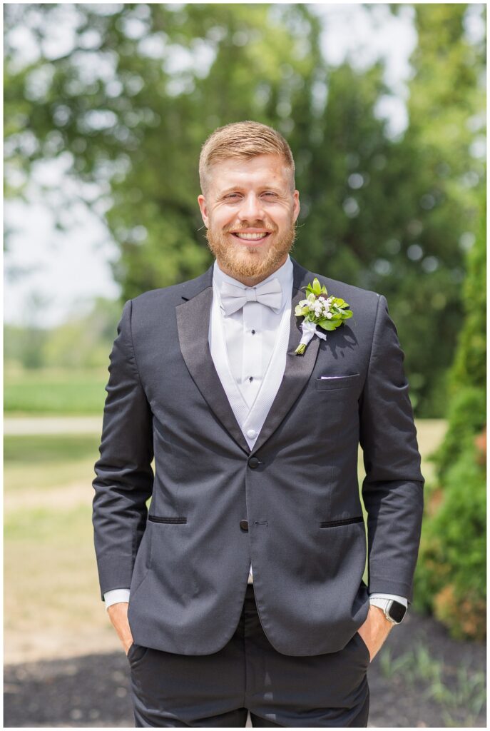 groom posing with his hands in his pockets outside the wedding venue