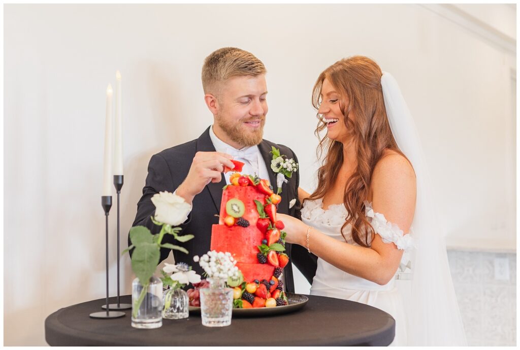 bride and groom cutting a watermelon fruit cake at the Barn at Seneca Hills