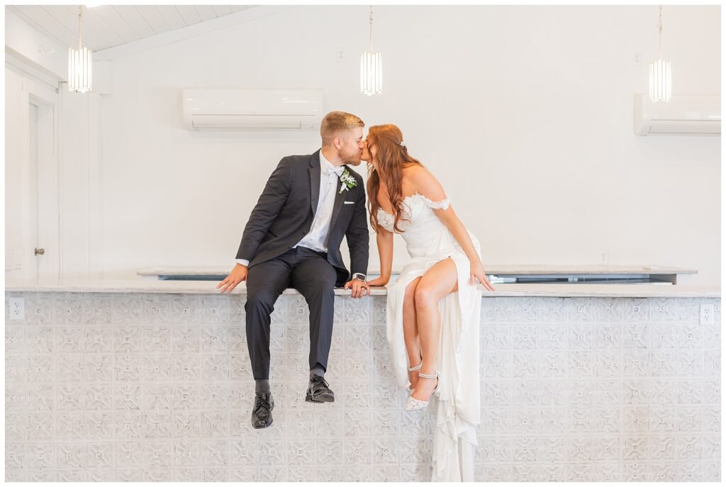 wedding couple sitting on a white tiled bar inside the Tiffin, Ohio barn venue