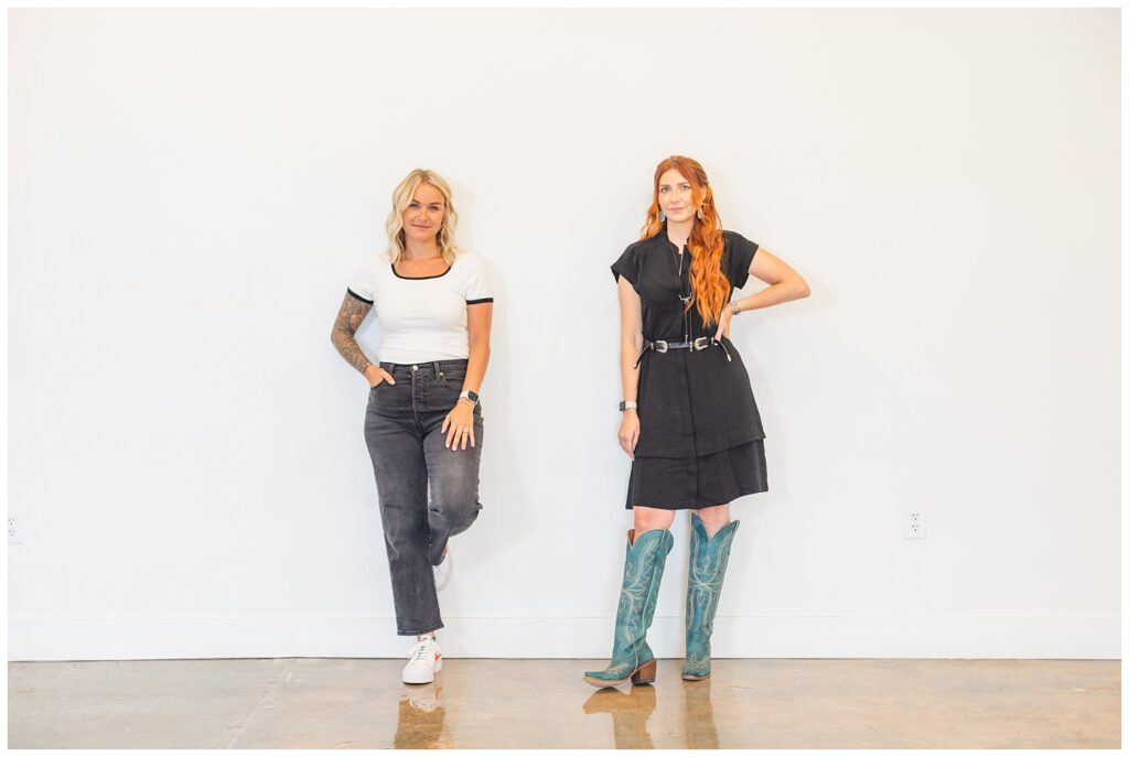 owners of The Lovely Lemon permanent jewelry business standing against a white wall at venue