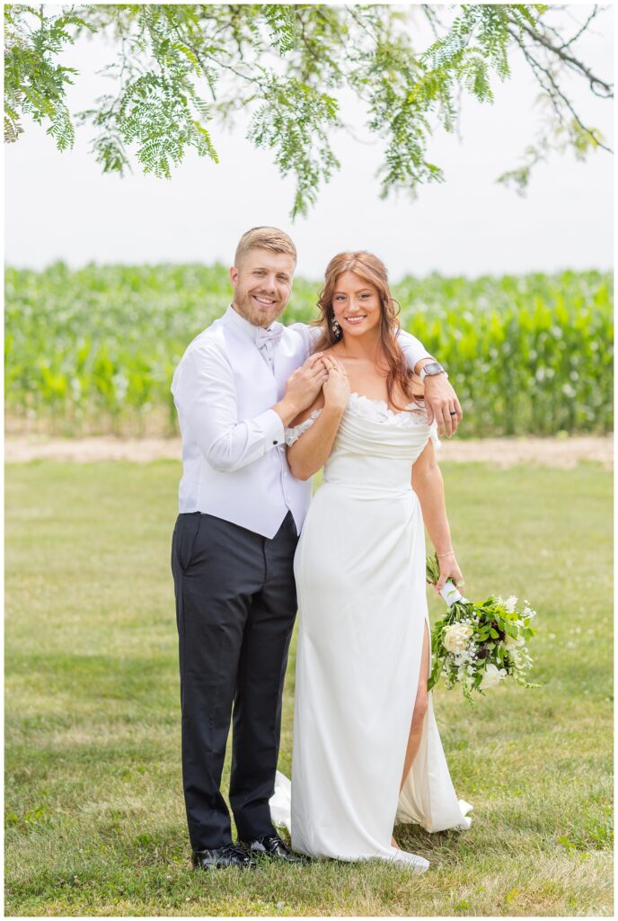 wedding couple posing under a tree near a corn field in Tiffin, Ohio