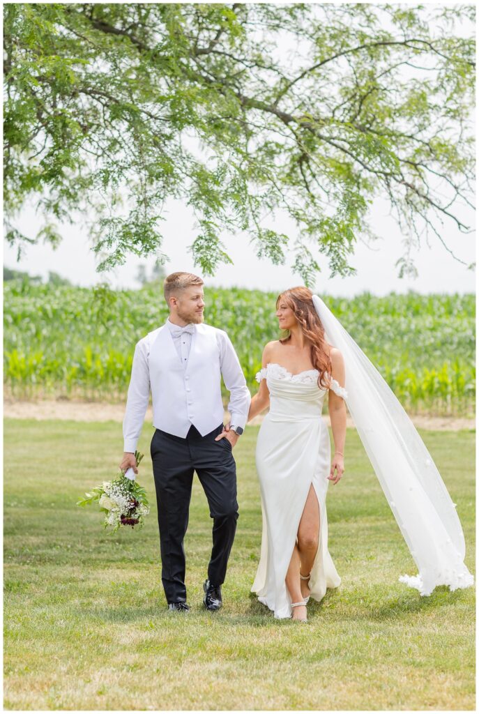 wedding couple walking together under a tree outside at a venue in Tiffin, Ohio