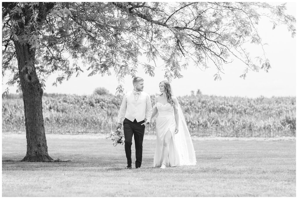 wedding couple posing outside while groom holds the bride's bouquet