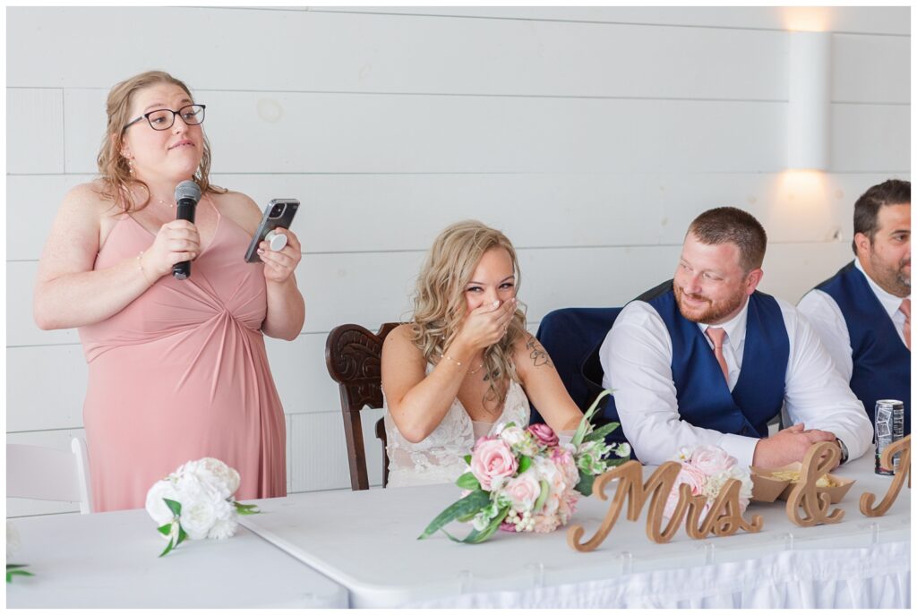 maid of honor giving a toast and making the bride laugh at reception