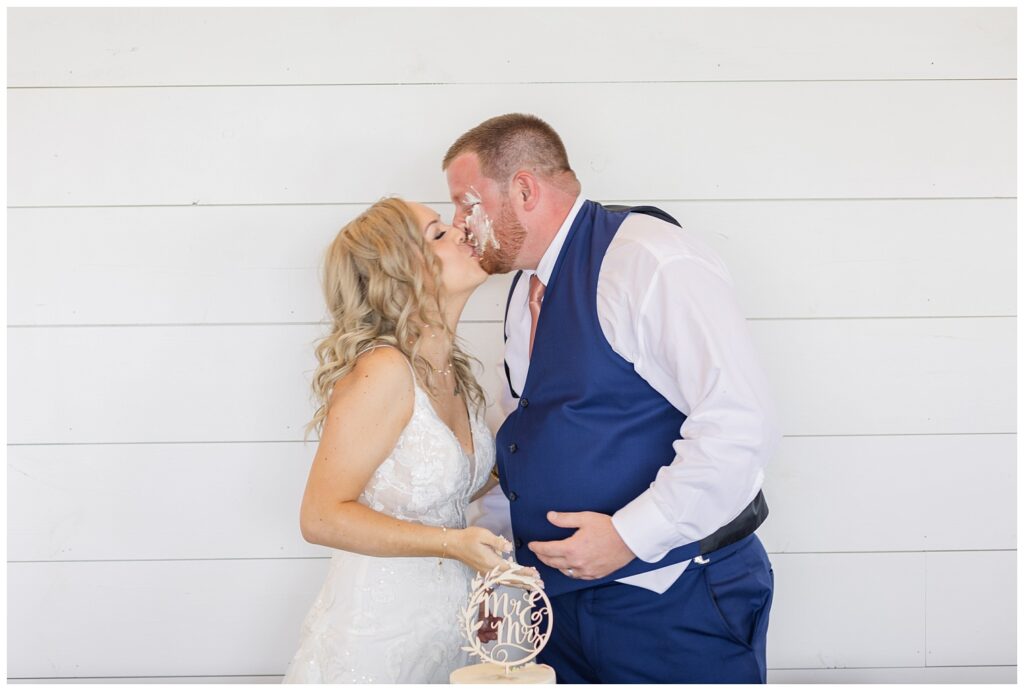 bride and groom share a kiss after cutting their cake at wedding reception