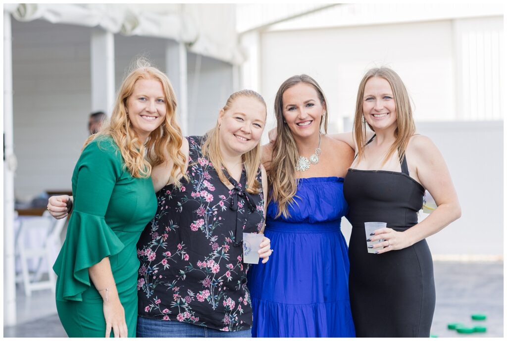 wedding guests posing and holding drinks at reception outside 