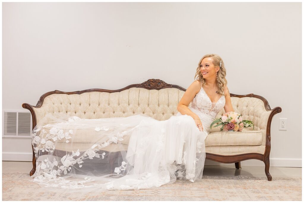 bride stretched out on a long white ivory antique couch holding her bouquet