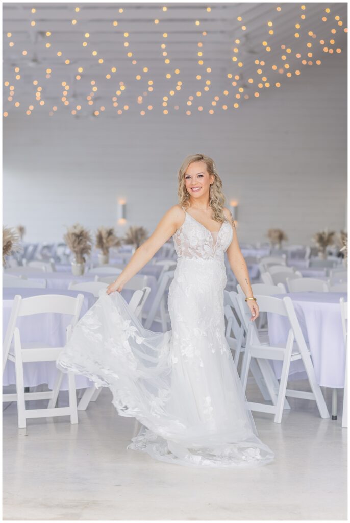 bride holding her train inside the Arlington Acres wedding venue next to reception tables