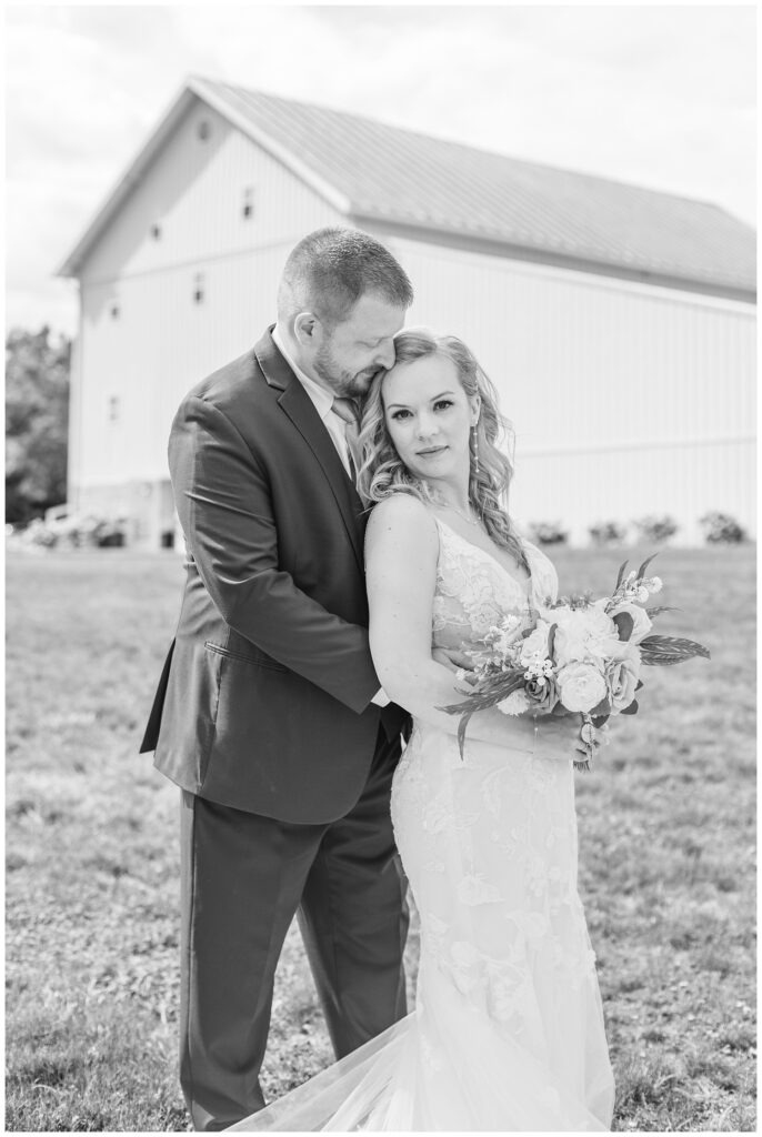 groom hugging the bride from the side while she is holding her bouquet