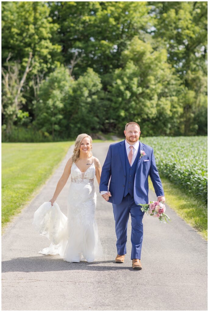 bride and groom walking on the road next to a field at Arlington Acres