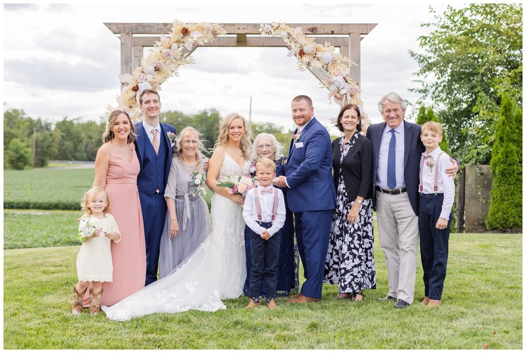 family formals in front of a wooden arch at Arlington Acres wedding venue