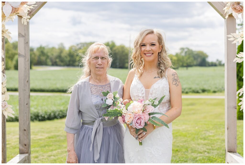 bride posing with her mom under the wooden arch at Arlington Acres