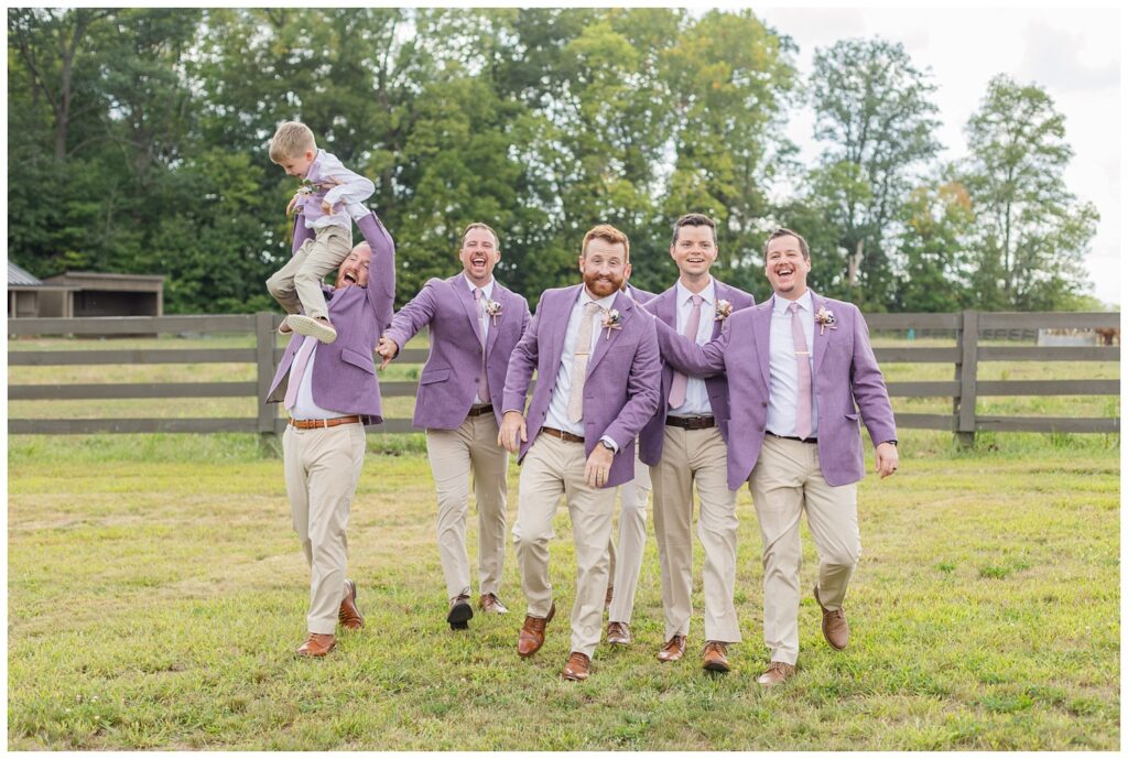 groomsmen walking together outside away from a fence at the Homestead by Stillwaters