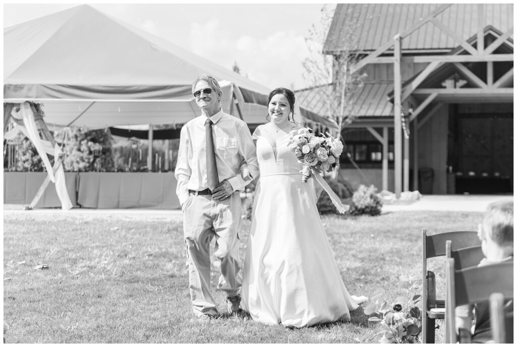 bride walking down the aisle outside with her dad at the Homestead by Stillwaters