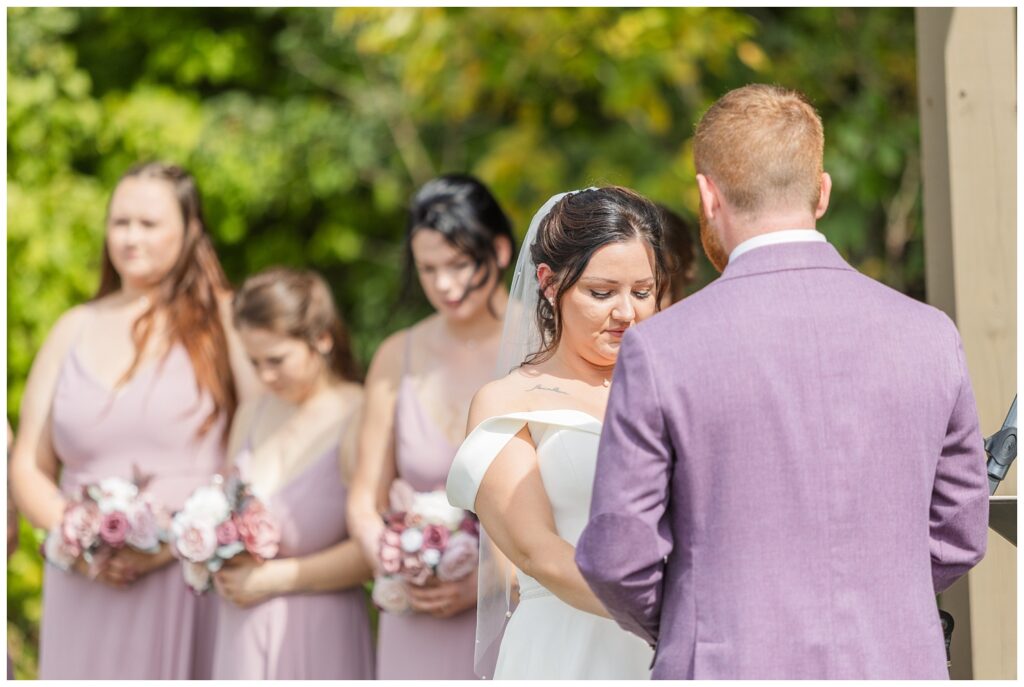 bride and groom praying together while holding hands at outdoors ceremony