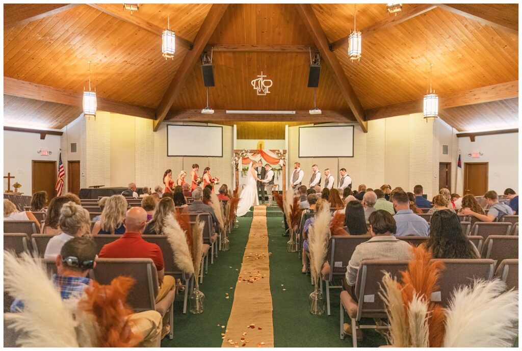 wide angle shot of the bride and groom getting married at the altar