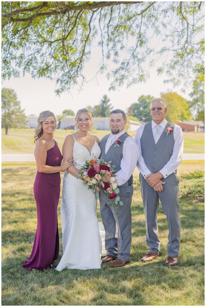 bride and groom posing with the bride's parents outside the church after the wedding ceremony