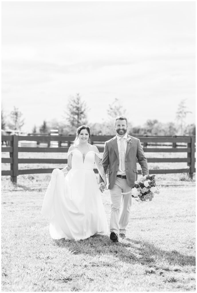 groom holding the bouquet while bride holds dress and walks together