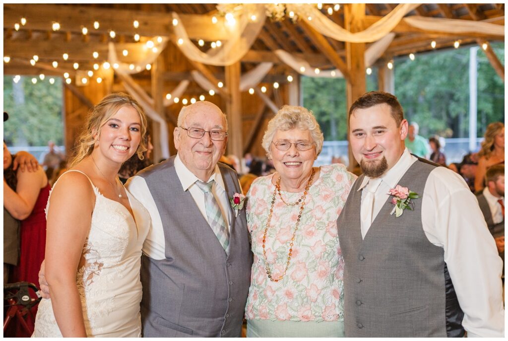 groom and bride posing with the bride's grandparents at wedding reception