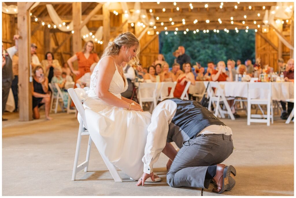 groom getting the garter off the bride's leg at summer wedding reception in Ohio