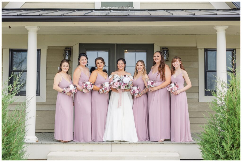 bride posing with her bridal party on the porch at the Homestead by Stillwaters venue