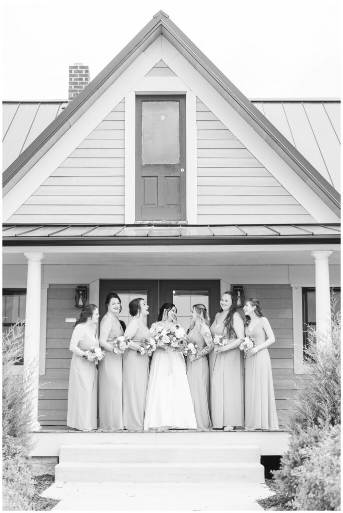 bride posing with her bridal party on the porch at the Homestead by Stillwaters venue