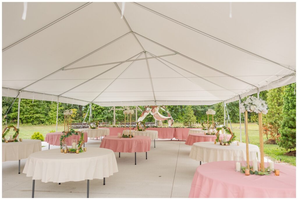 reception tables with white and ivory cloths under a white tent outside