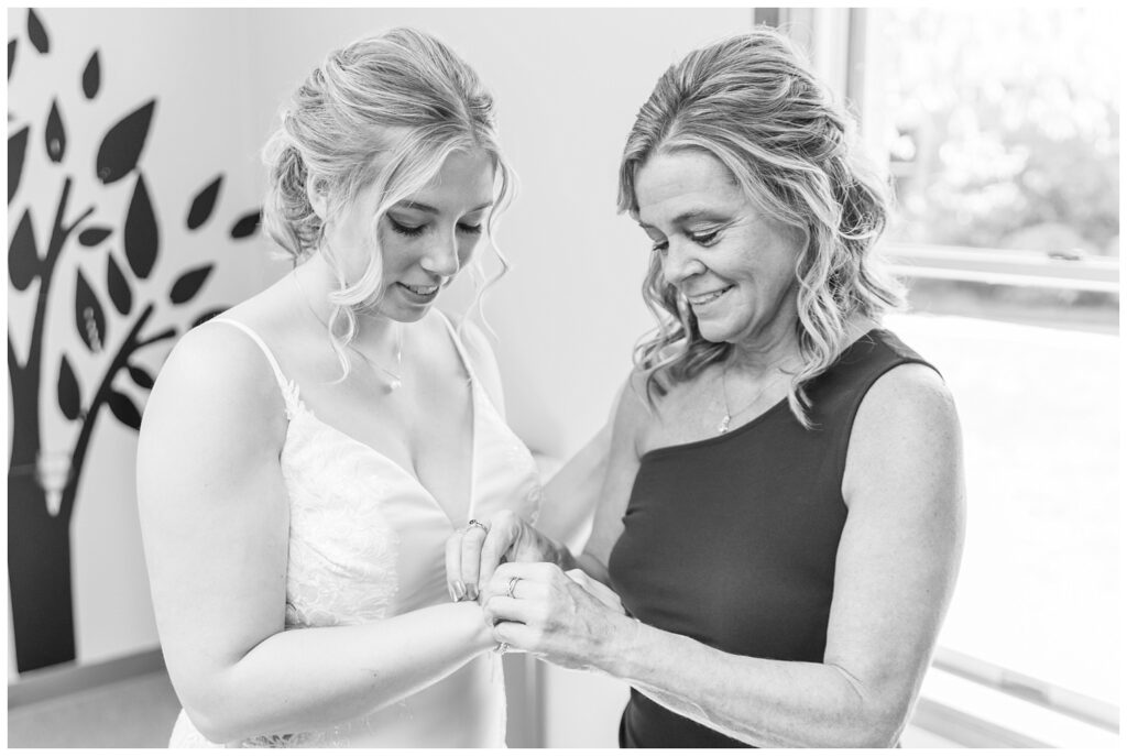 bride's mom helping the bride put on her bracelet while getting ready