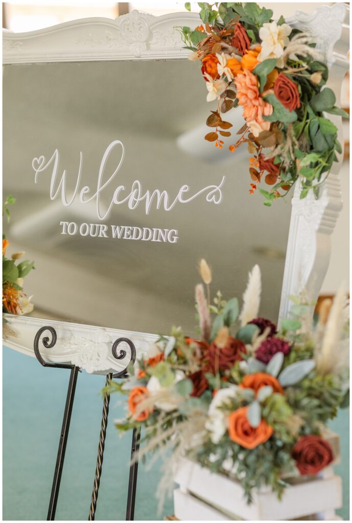 welcome mirror adorned with fresh flowers at the wedding ceremony 