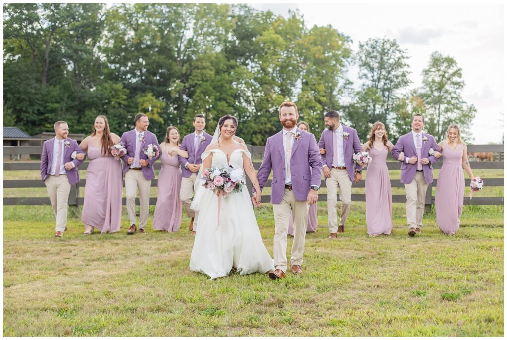 full wedding party walking together in front of a fence at the Homestead by Stillwaters