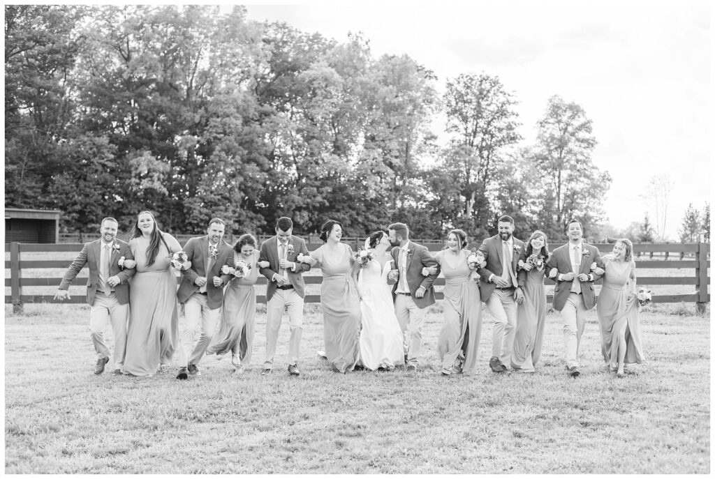 full wedding party linking arms and walking together for portraits outside 