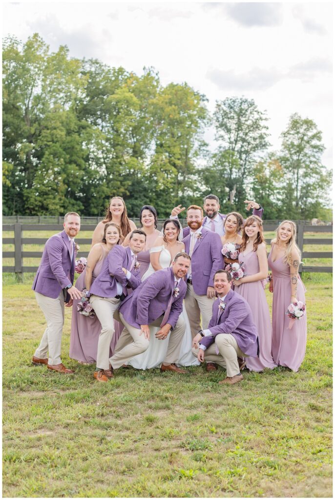 bridal party crowded around the bride and groom outside at wedding venue 