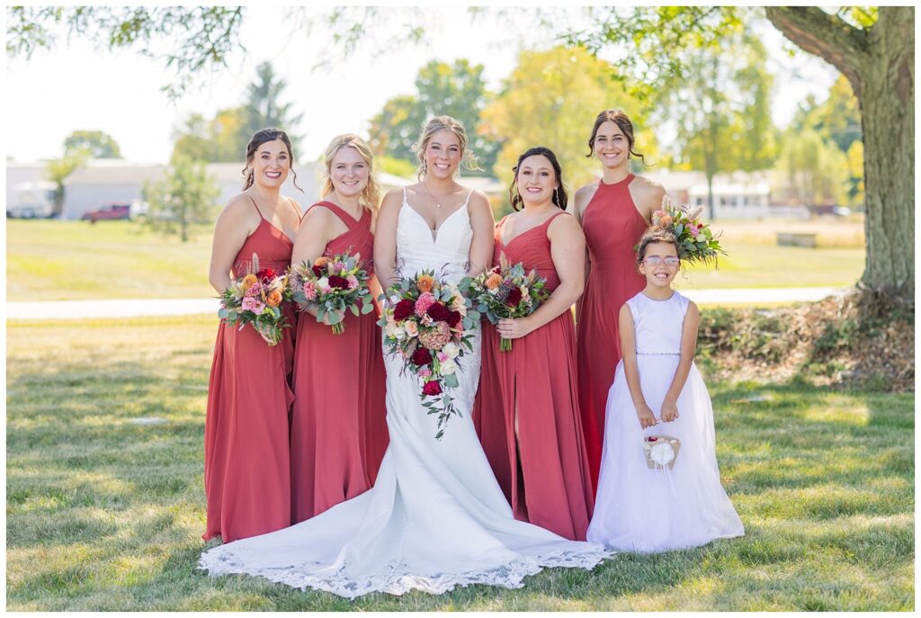 bride and her bridal party posing outside under a tree before the ceremony