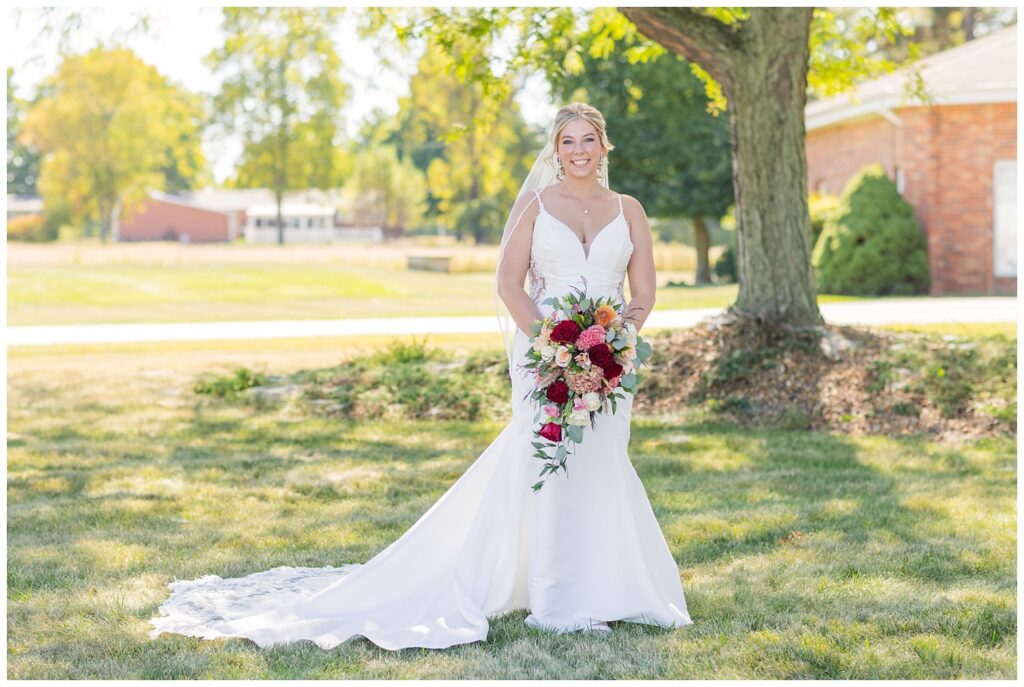 bride posing with her bouquet outside the church next to a tree in Norwalk, Ohio