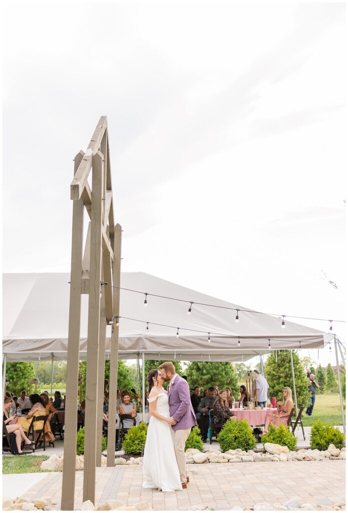 wedding couple share a kiss after their first dance on the patio outside