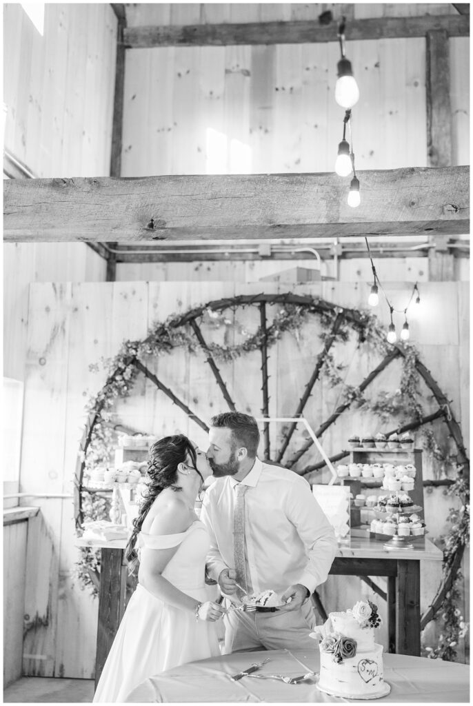 bride and groom sharing a kiss after cutting the cake together at the Homestead by Stillwaters